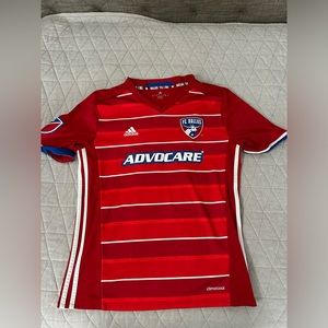 Two soccer jerseys. One is dallas fc and one is from a club team dynamo fc
